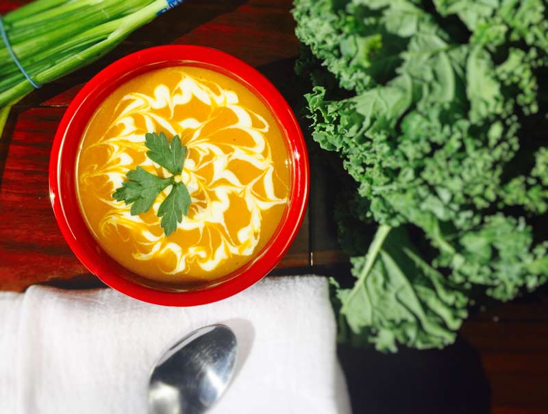 Kabocha Squash Soup in bowl with sour cream and spoon