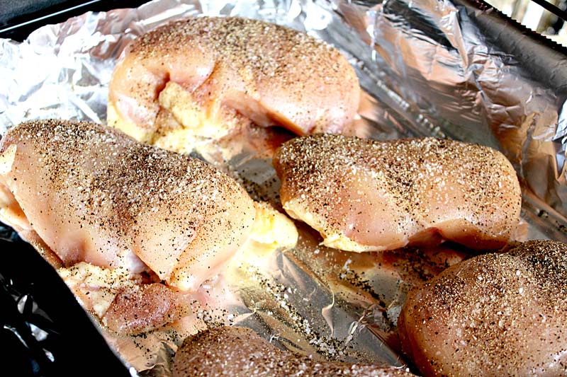 Chicken thighs seasoned and ready to roast in a pan