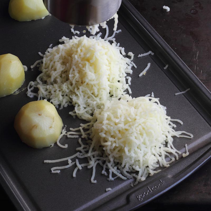 Baked steamed potatoes on baking sheet using potato ricer