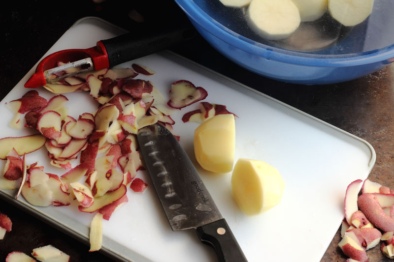 Peeled potato on cutting board with knife